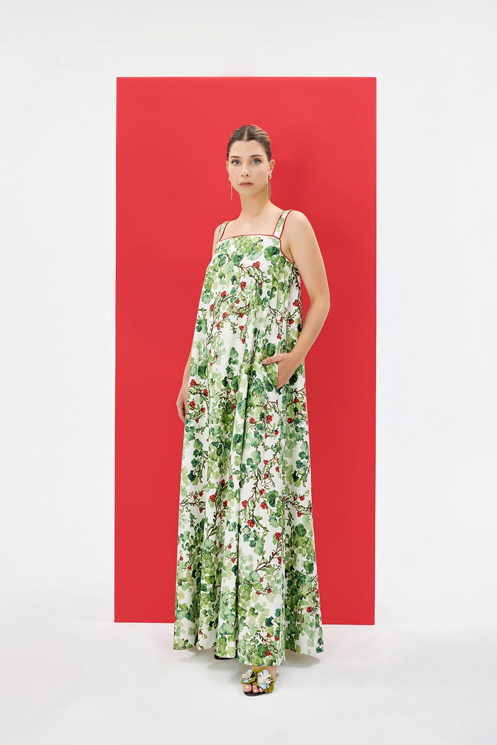 ARLENA %100 Pamuk Elbise - Yeşil | ARLENA elbise, yeşil desen ve kırmızı biye ile net bir duruş sergiler. Kare yaka ve pelerin detayları %100 pamuk yapısıyla ferah his sunar.