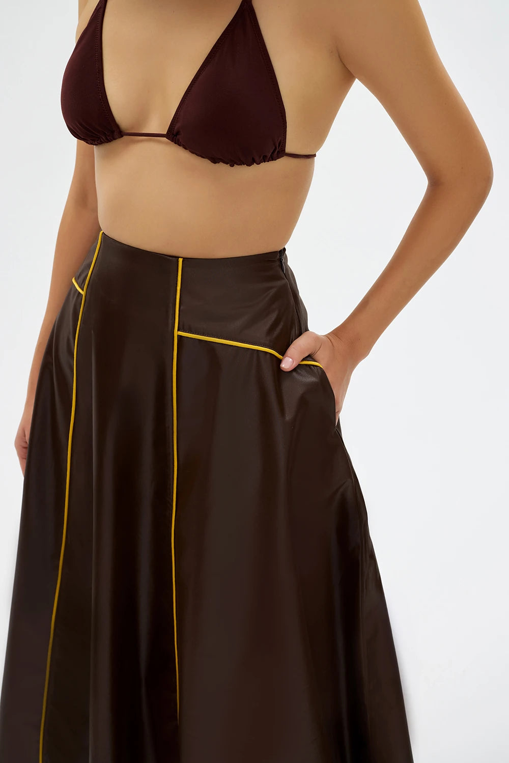 VESERA Etek - Kahverengi | Pamuk ağırlıklı deri dokulu VESERA Etek, sarı biye detayıyla yaz şıklığını sunar. Rahat kesimiyle gün boyu ferahlık ve zarif bir siluet sağlar.
